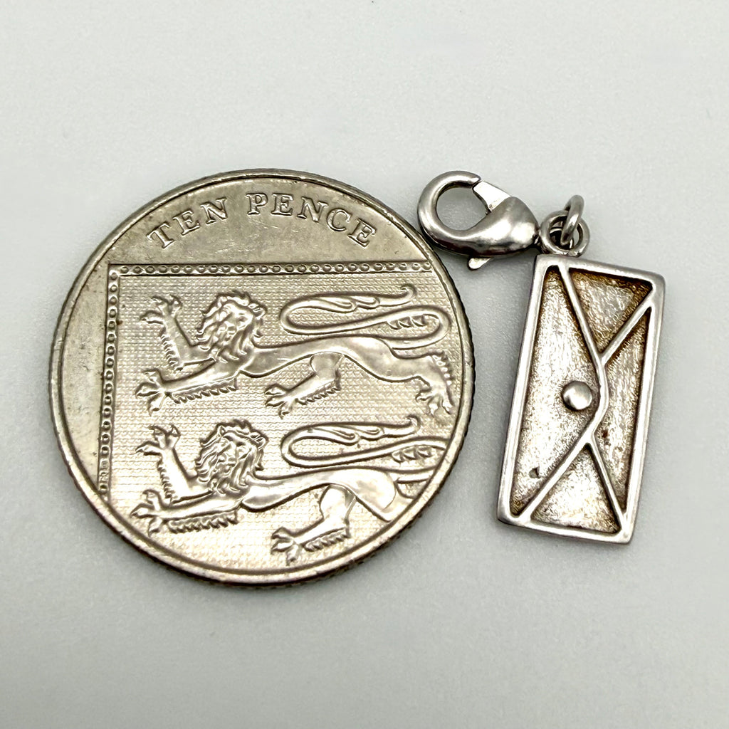 A sterling silver charm shaped like a vintage British ten pence coin next to a matching rectangular envelope pendant, displayed on a light gray background.
