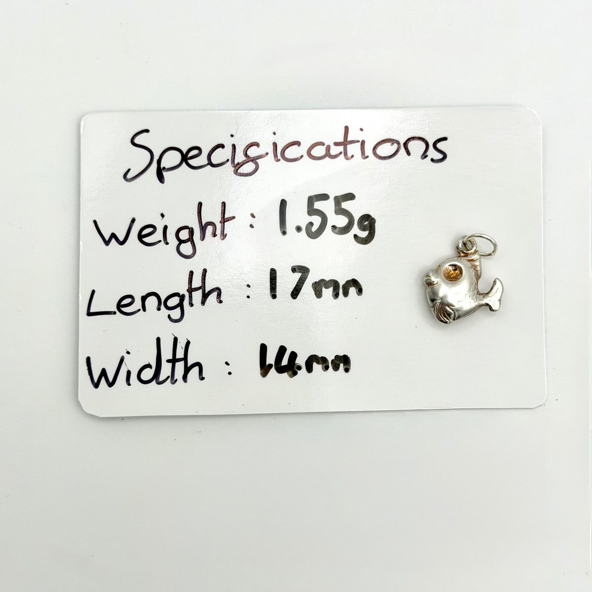 Vintage sterling silver fish charm viewed at an angle from below showing the underside and suspension ring