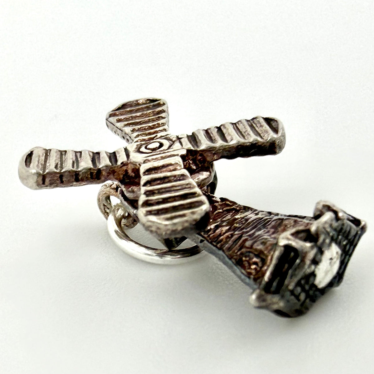 Angled close view of sterling silver windmill charm showing textured sails and base