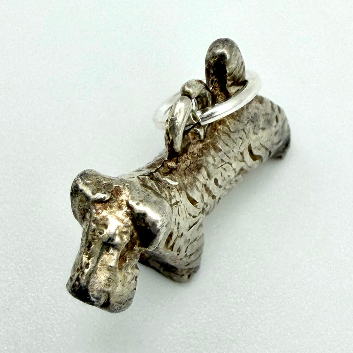 Vintage silver terrier dog charm beside a ten pence coin for scale