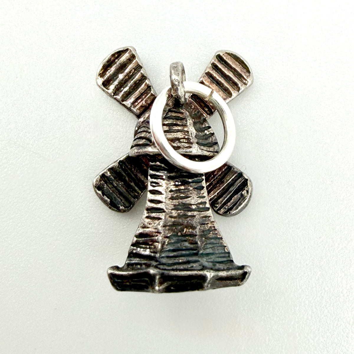 Back of vintage silver windmill charm showing jump ring and textured metal