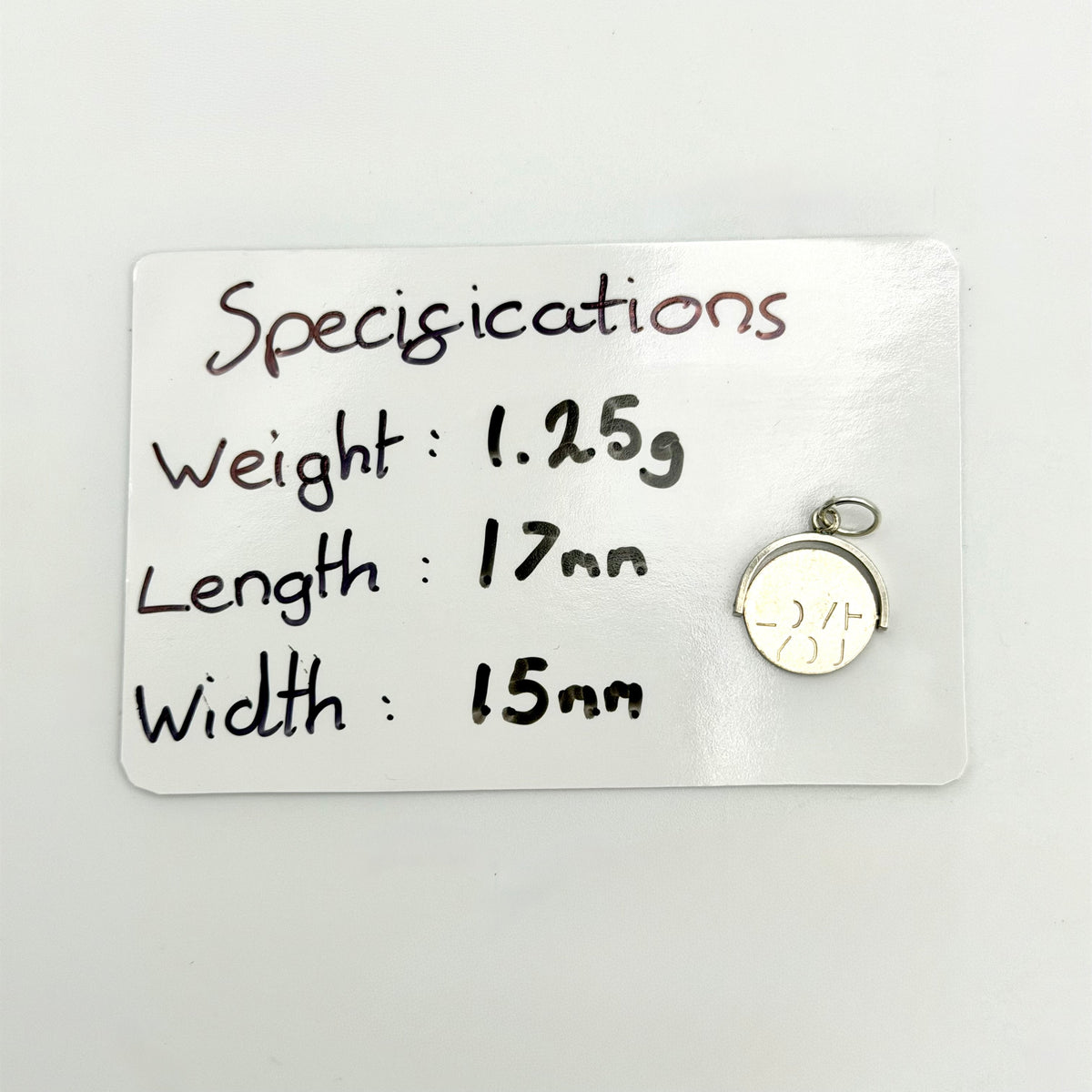 Sterling silver spinning fob charm beside its handwritten size and weight details