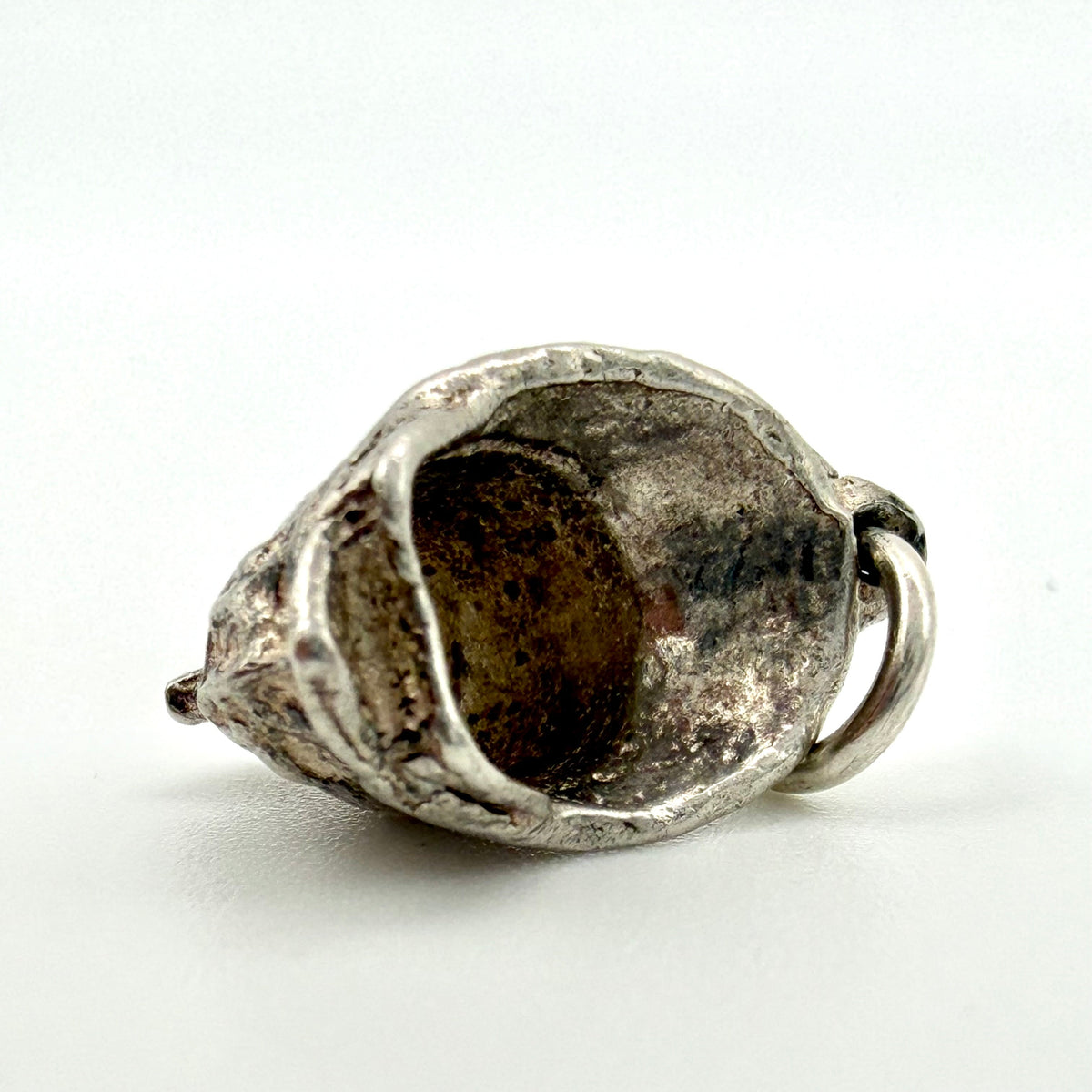 A sterling silver pendant shaped like a fireman’s helmet with a small integrated ring, photographed on a clean white background.
