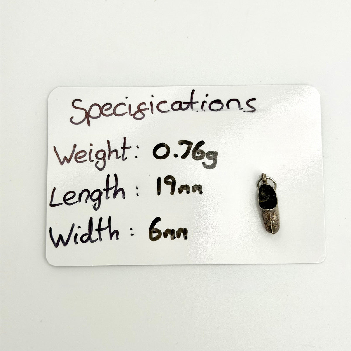 Dutch clog charm beside handwritten measurements of 19mm length, 6mm width and 0.76g weight