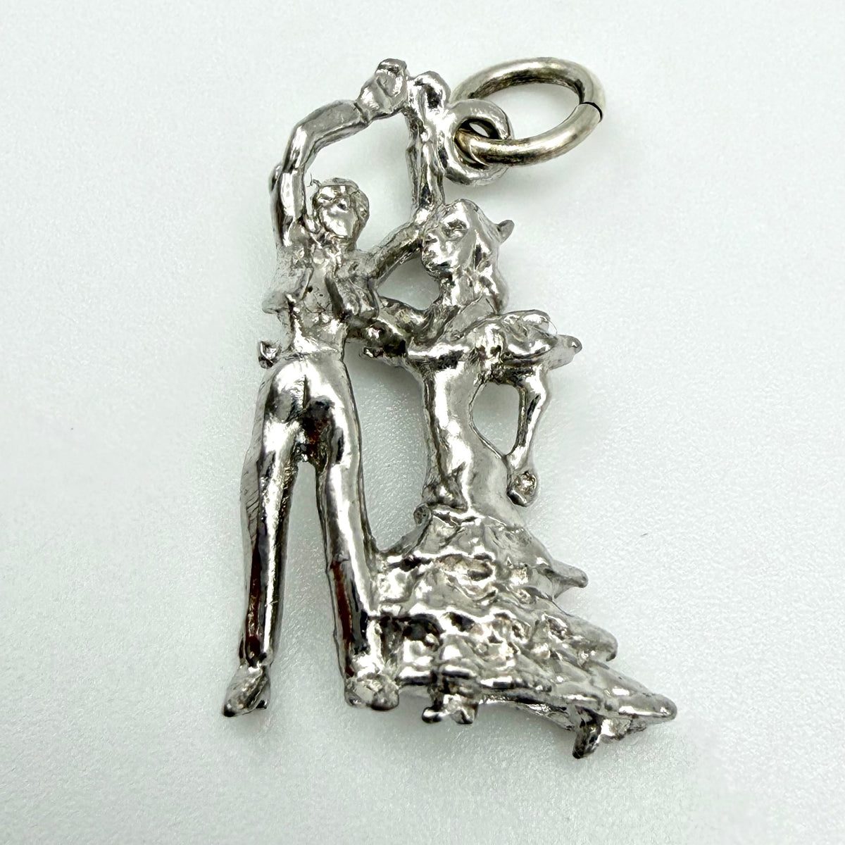 A sterling silver pendant featuring a dancing couple, shown on a plain light background.