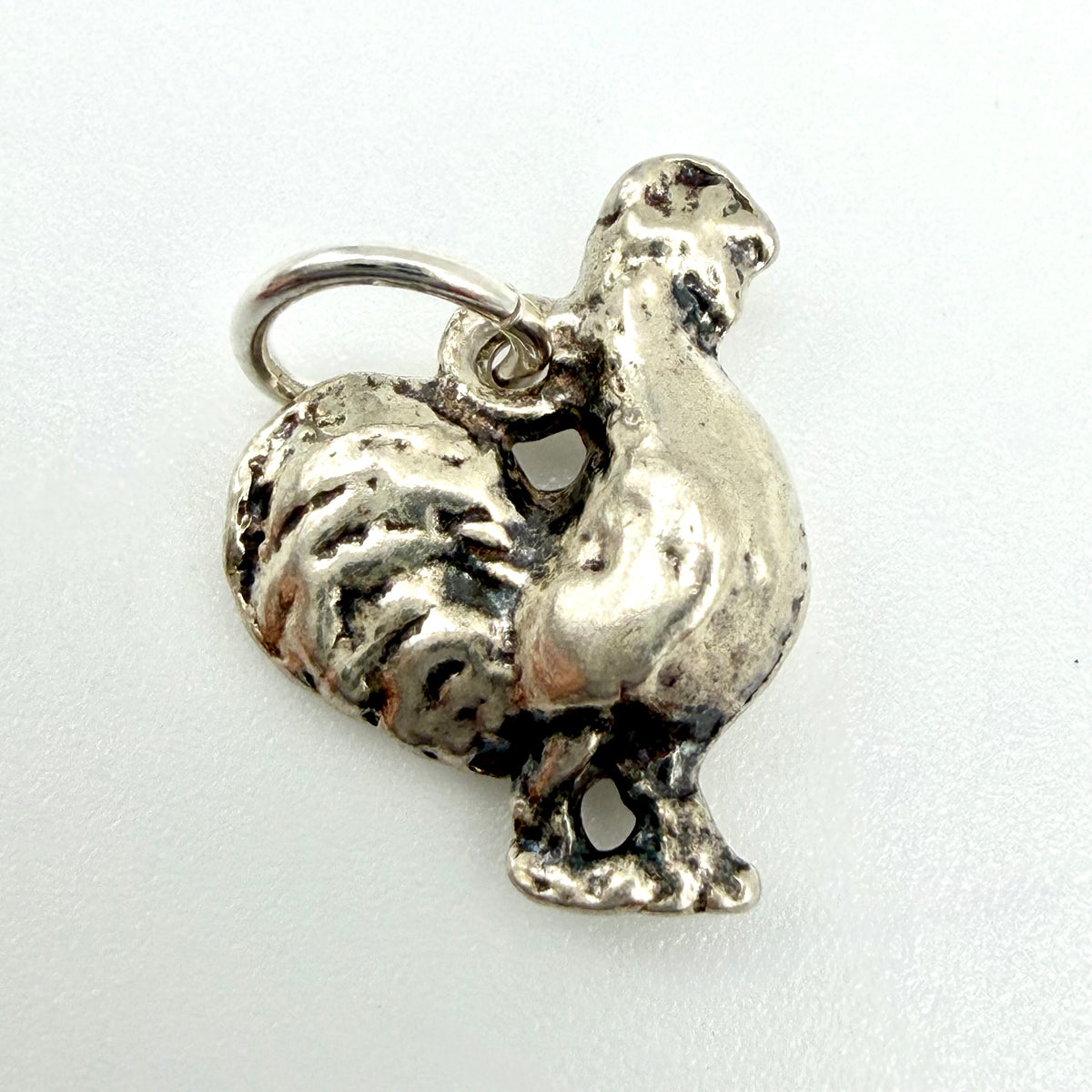 A sterling silver rooster charm pendant with a textured finish and a hanging loop, shown on a plain white background.