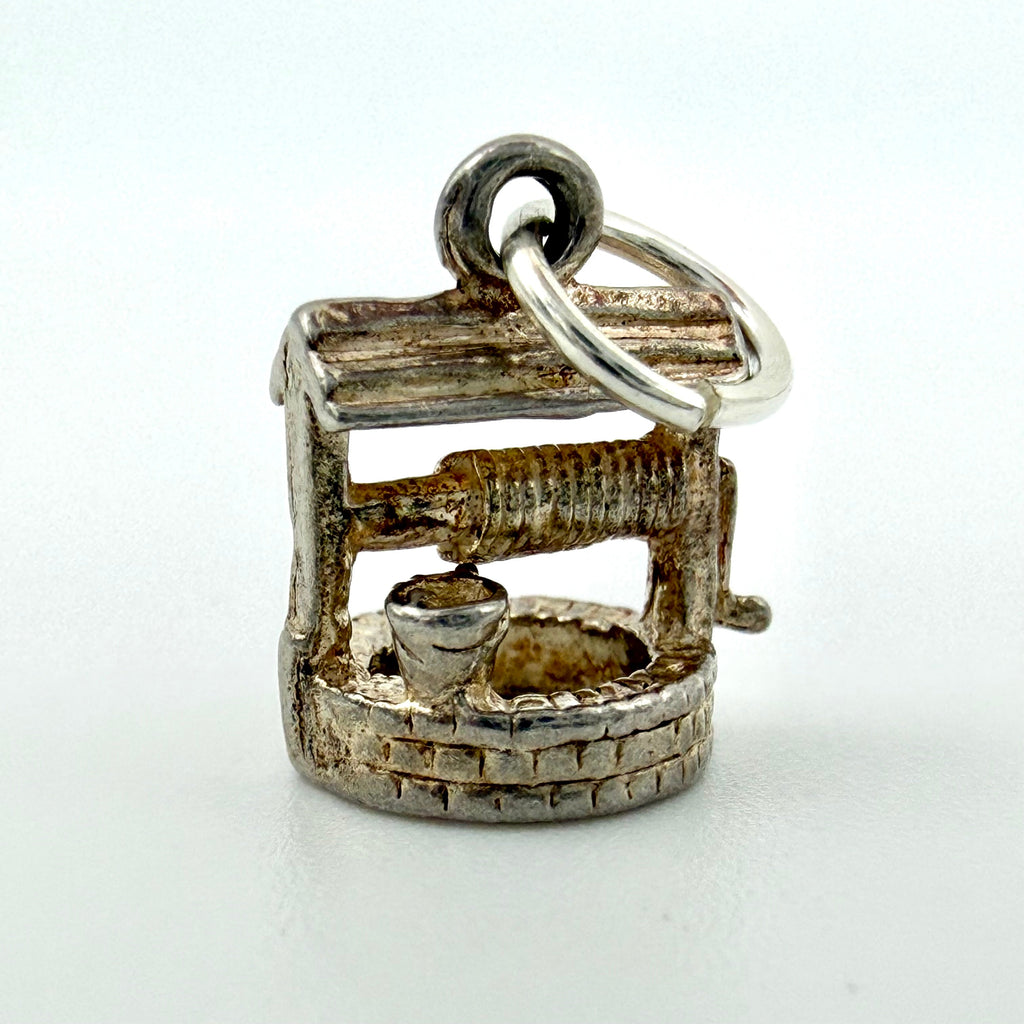 Angled view of vintage sterling silver wishing well charm with hanging ring