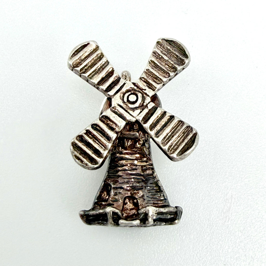 Vintage sterling silver windmill charm beside a ten pence coin for scale