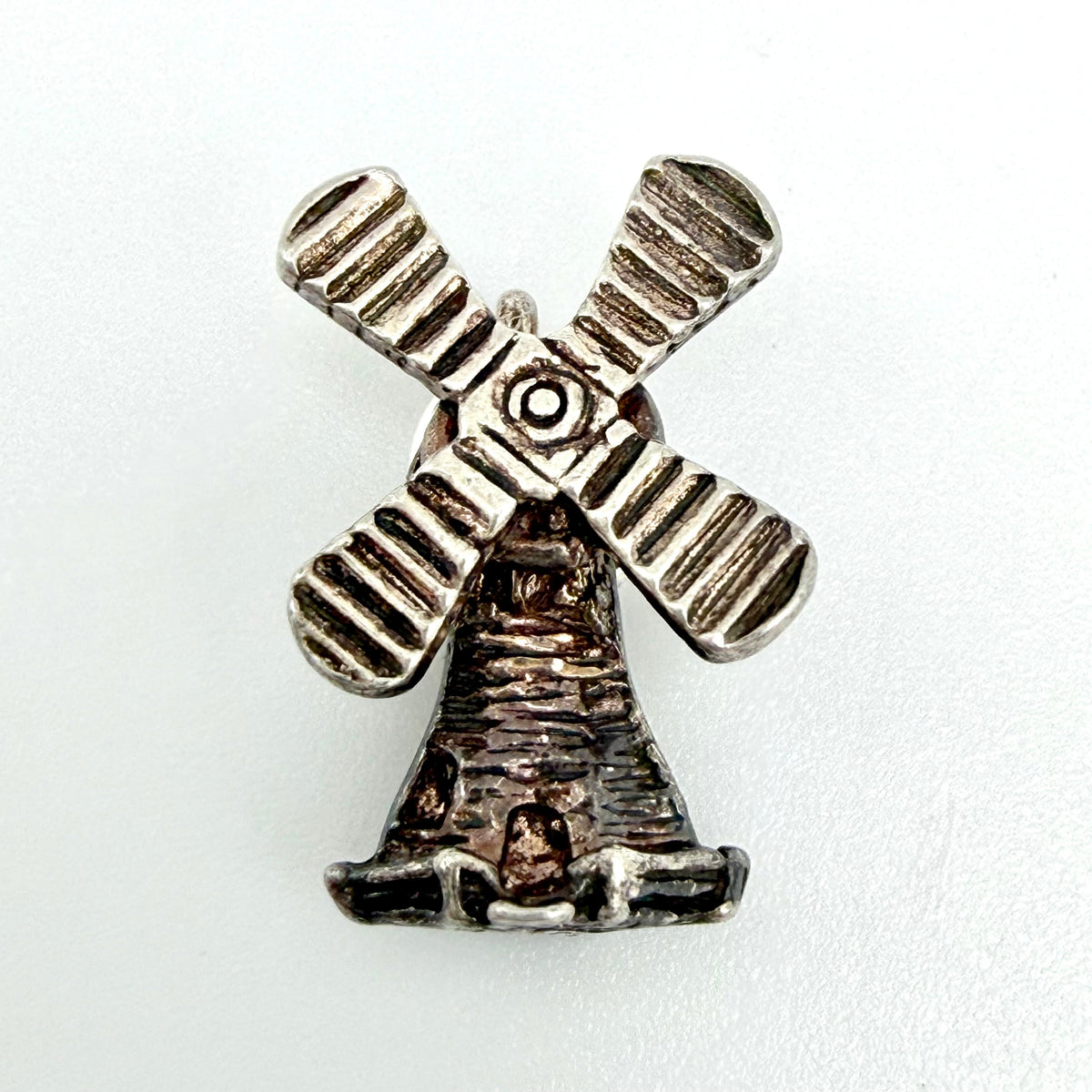 Vintage sterling silver windmill charm beside a ten pence coin for scale