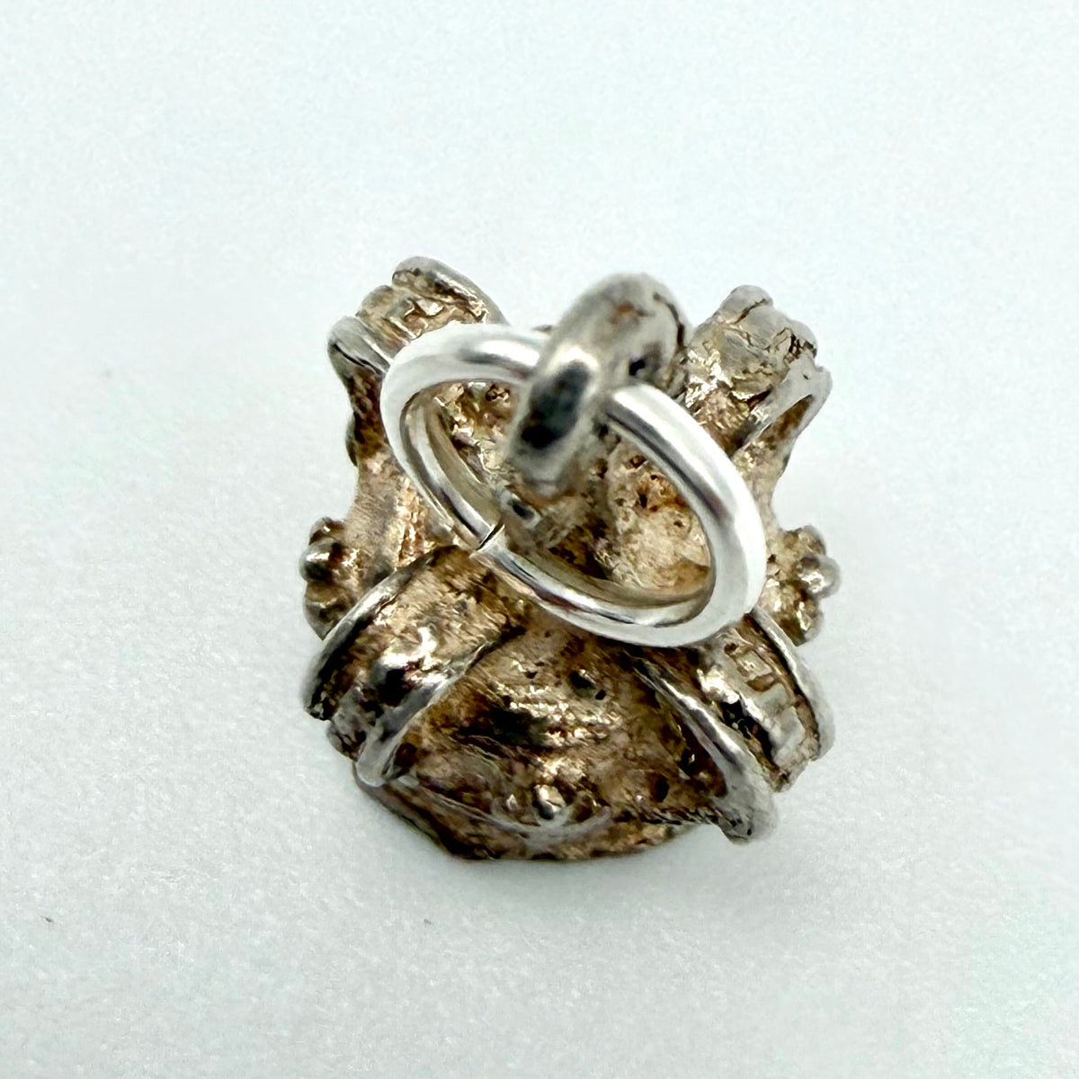 Vintage silver crown charm beside a ten pence coin for scale