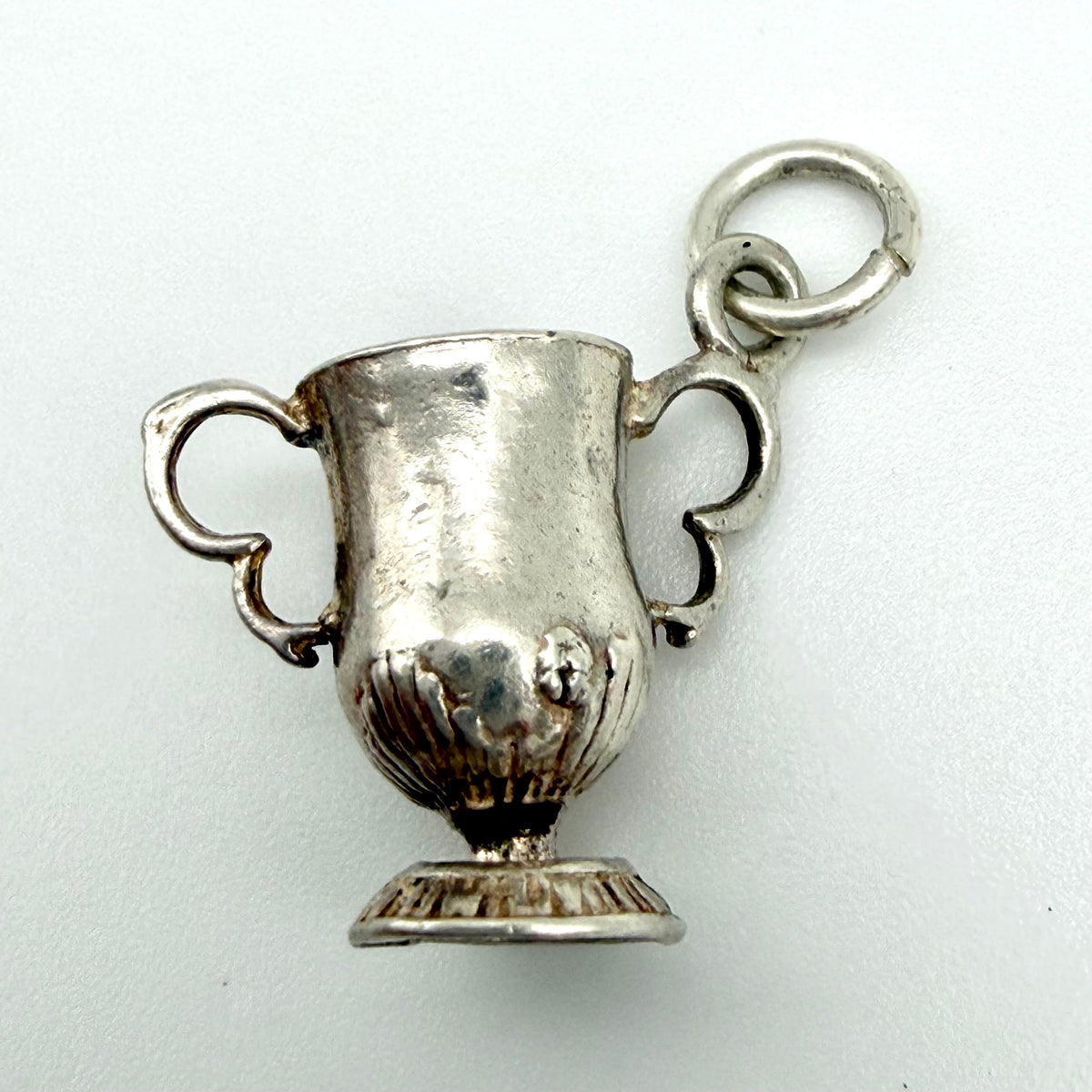 A silver trophy cup charm with two handles and a hanging loop, shown on a plain light background.