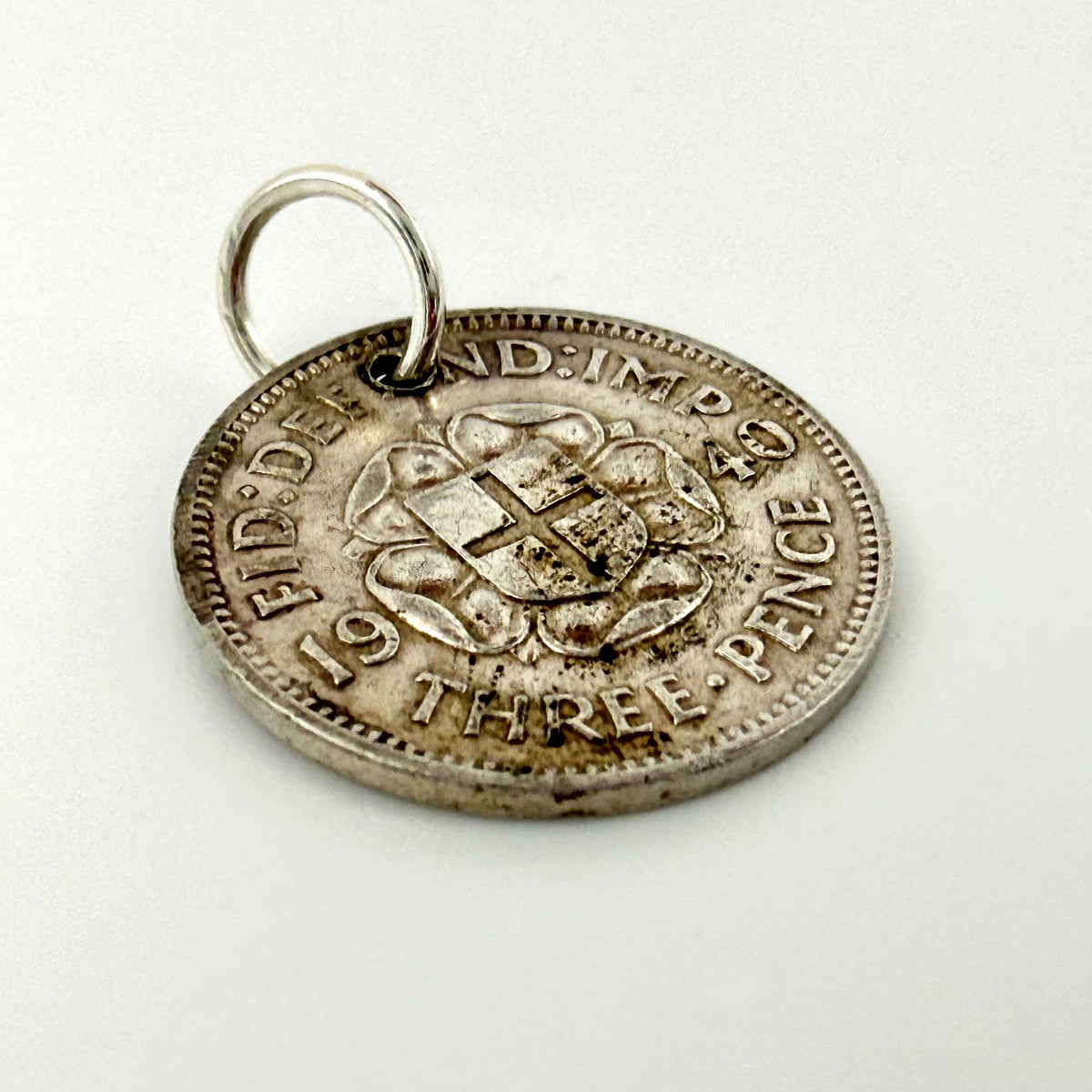 1940 British threepence coin charm beside handwritten measurements of 16mm and 1.48g
