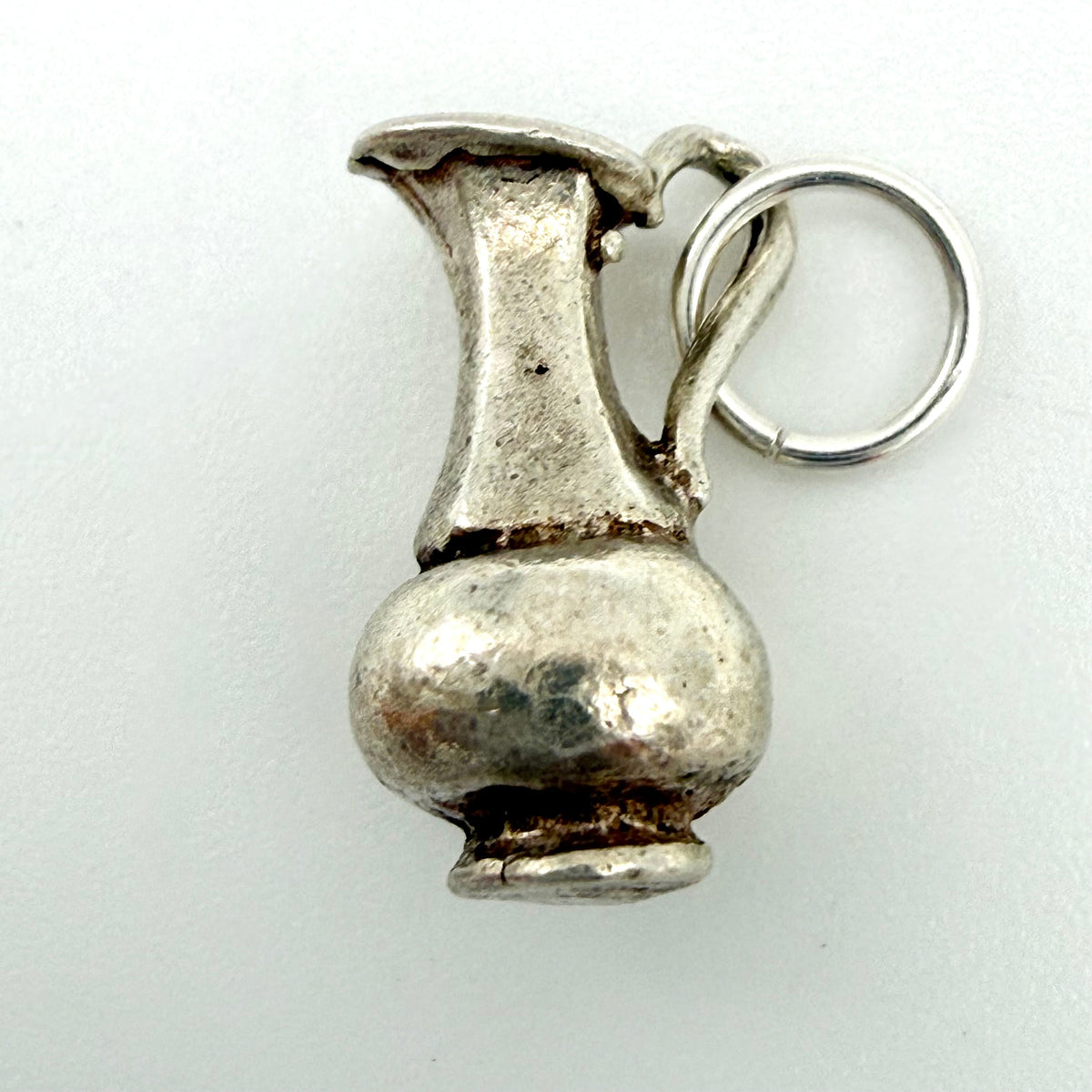 Vintage silver water jug charm beside handwritten measurements showing 2.67g weight, 15mm length and 8mm width