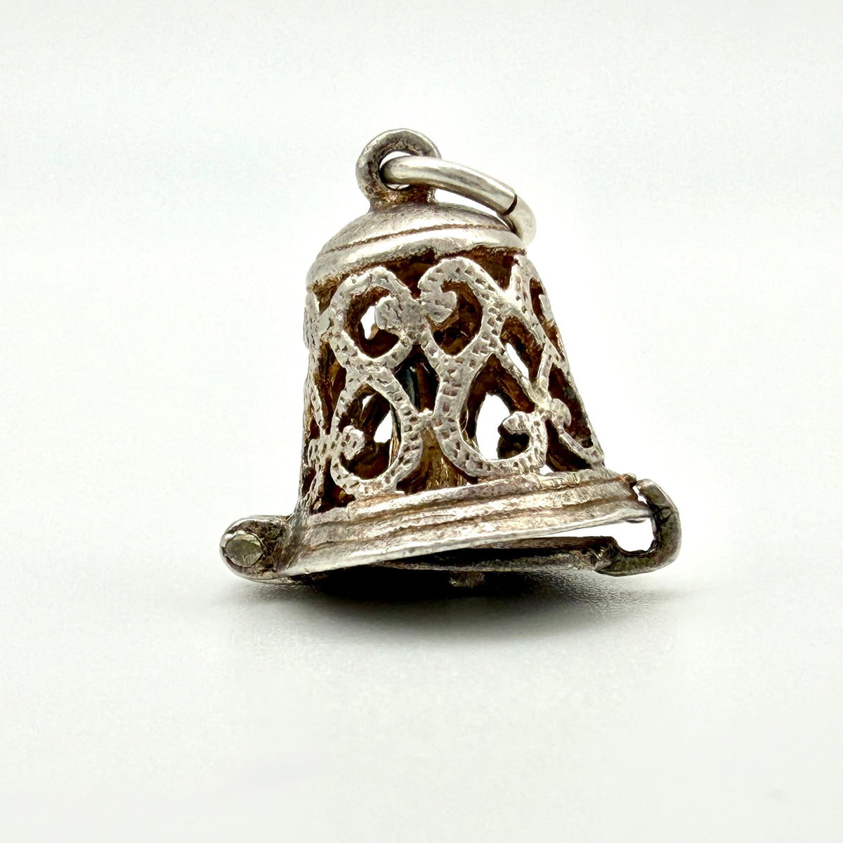 A vintage sterling silver filigree bell charm, shown on a clean white background.