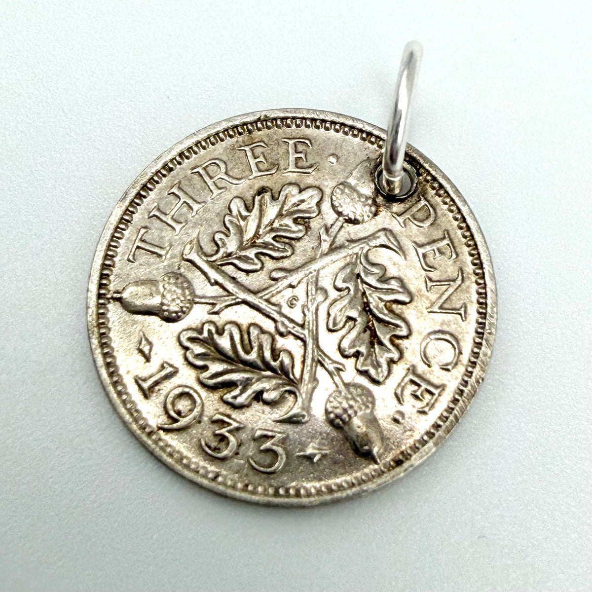 Angled view of 1933 threepence charm with oak leaves, acorns and hanging loop