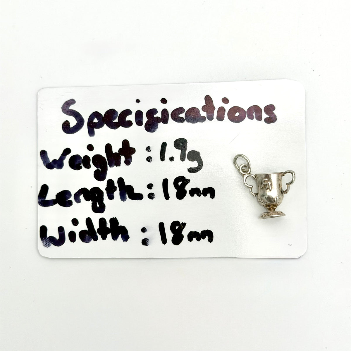 A small silver trophy cup charm with a hanging loop, displayed next to a white card that lists its specifications: weight 1.9g, length 18mm, and width 18mm.