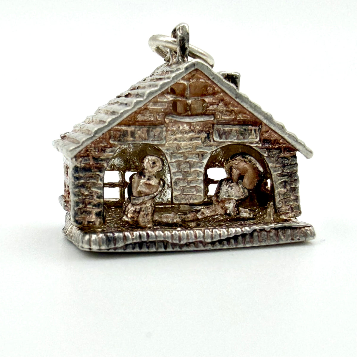 A sterling silver charm shaped like a rustic cabin or house with a small hanging loop at the top, photographed on a plain white background.