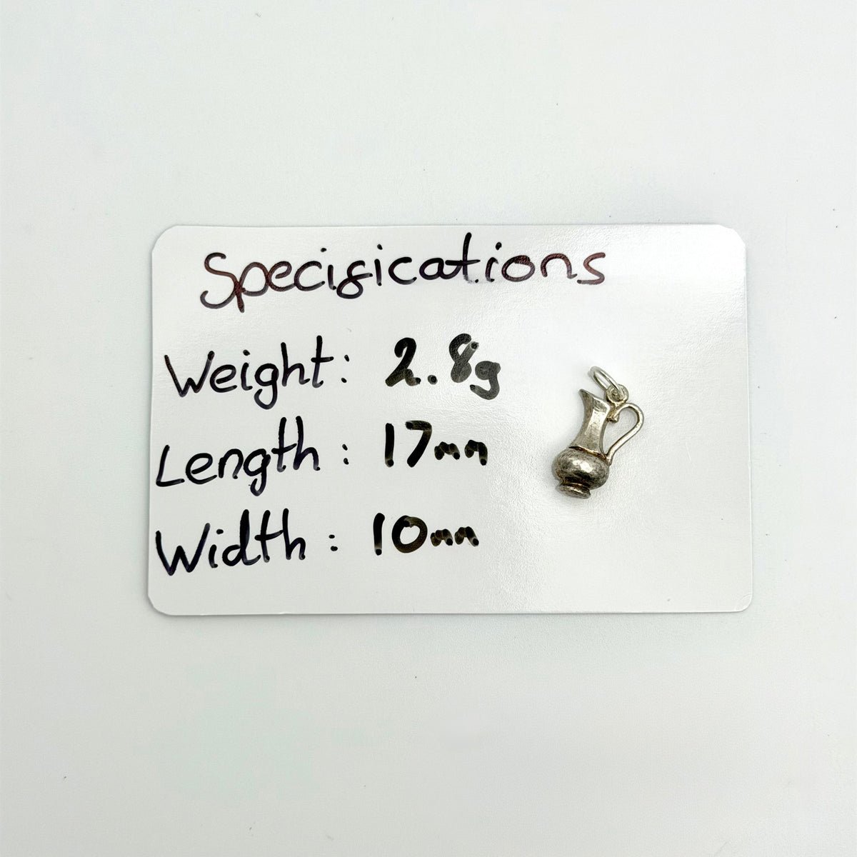 A small silver accessory shown next to a white card with handwritten specifications reading 'specifications', 'Weight: 2.8g', 'Length: 17mm', and 'Width: 10mm'.