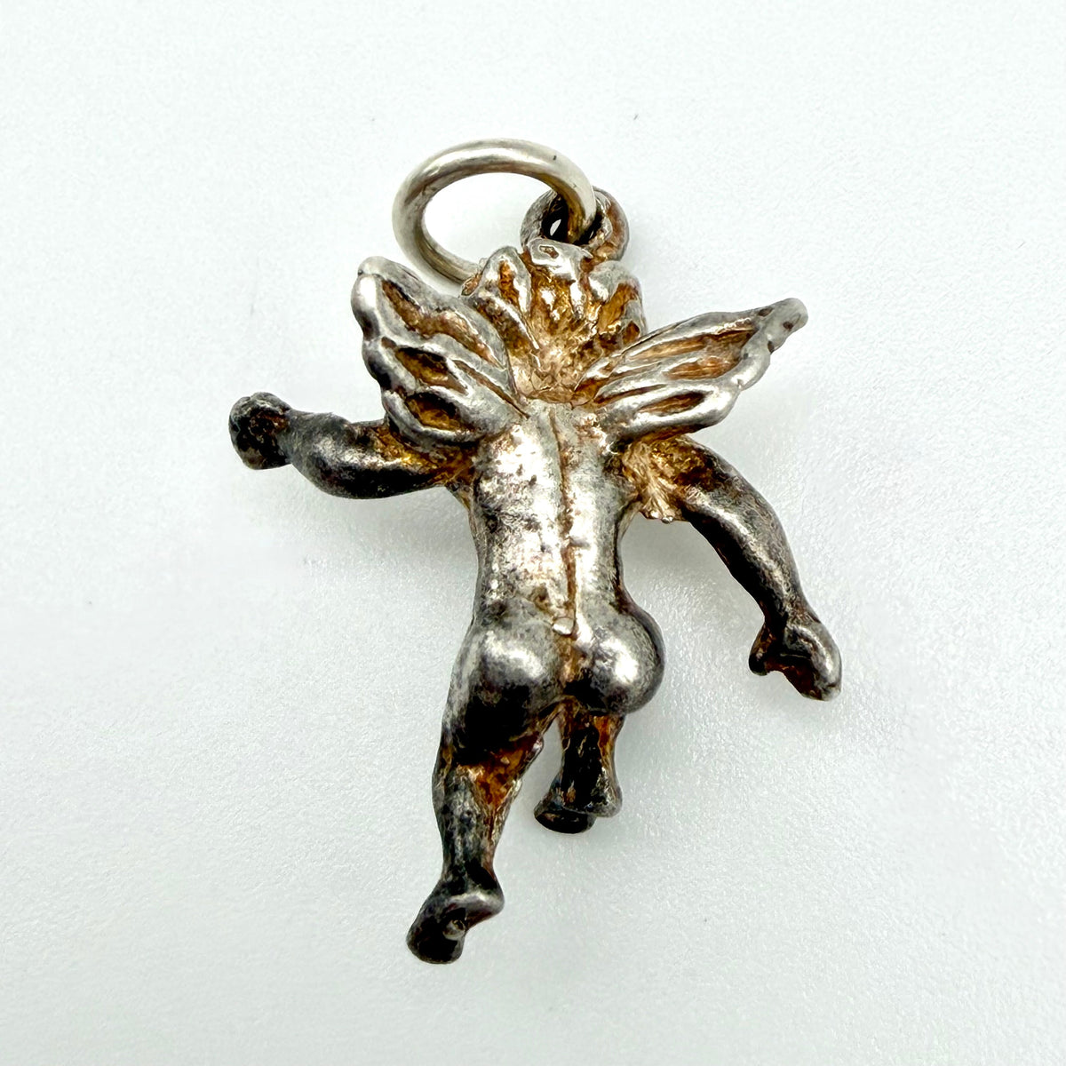 A small metallic cherub or cupid pendant charm with wings and a loop at the top, shown on a plain light background.