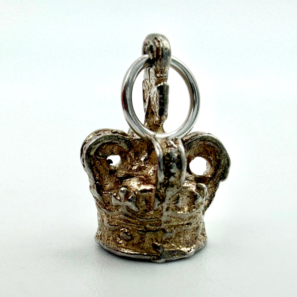 Crown charm beside handwritten card showing weight 1.65 g, length 15 mm and width 9 mm