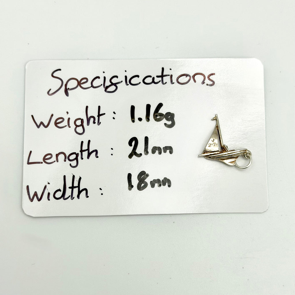 Sailboat charm shown next to a UK ten pence coin for size comparison