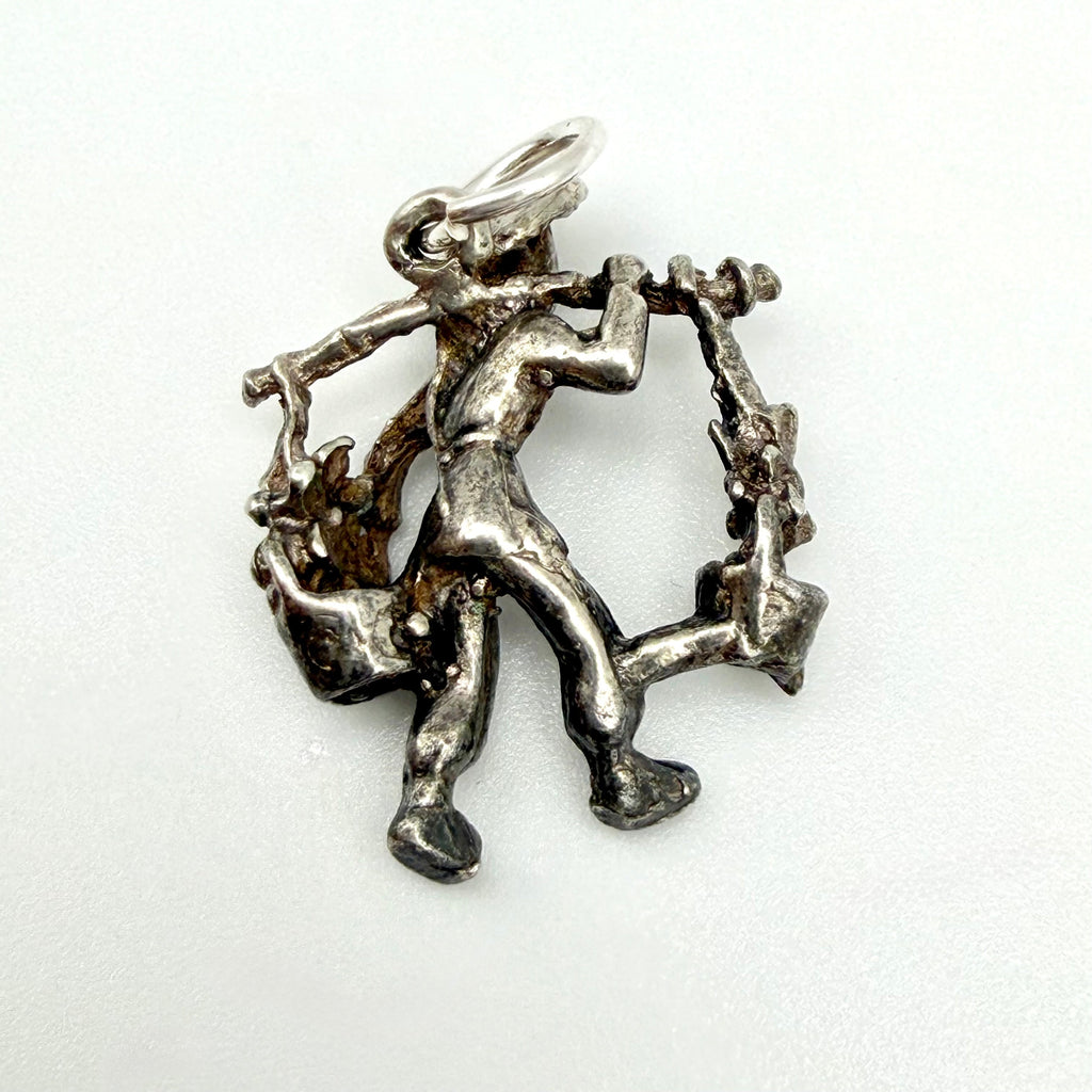 Rear view of the water carrier charm showing the pole, hanging vessels and attachment ring