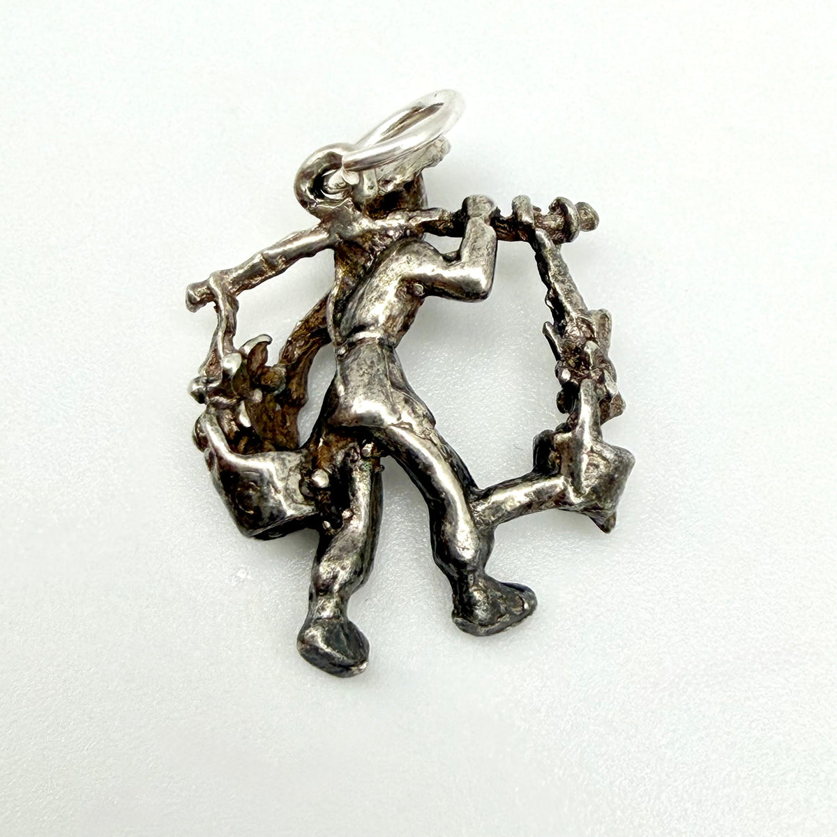 Rear view of the water carrier charm showing the pole, hanging vessels and attachment ring
