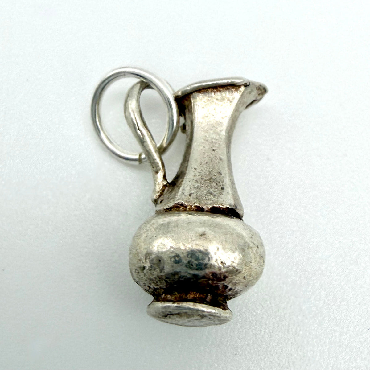 Front view of vintage sterling silver Aquarius water jug charm showing spout, handle and hanging ring