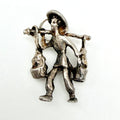 Front of vintage sterling silver water carrier charm beside a ten pence coin