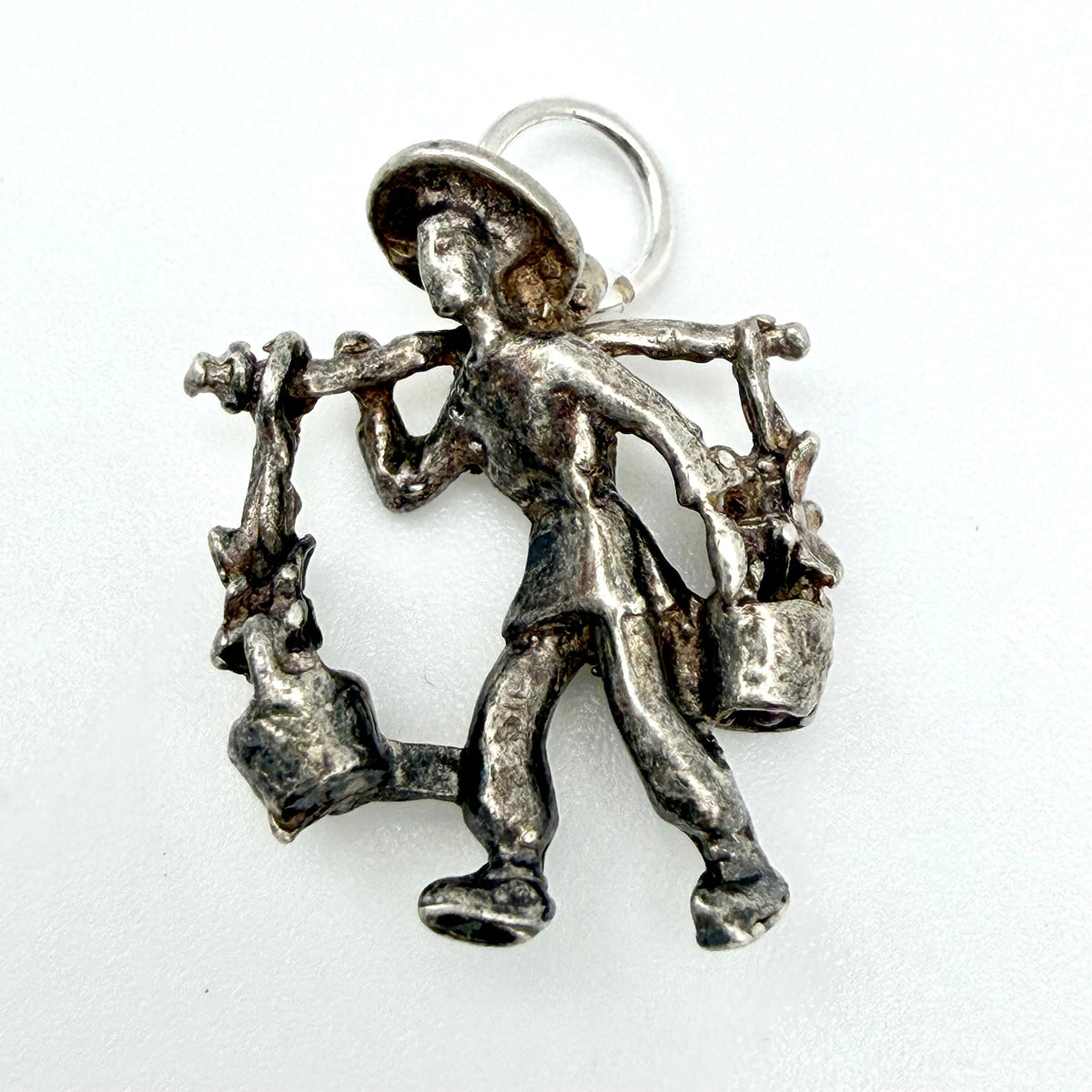 Water carrier charm beside a handwritten card showing its weight and measurements