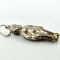 A silver pendant shaped like a reclining figure, attached to a silver ring, photographed on a plain light background.