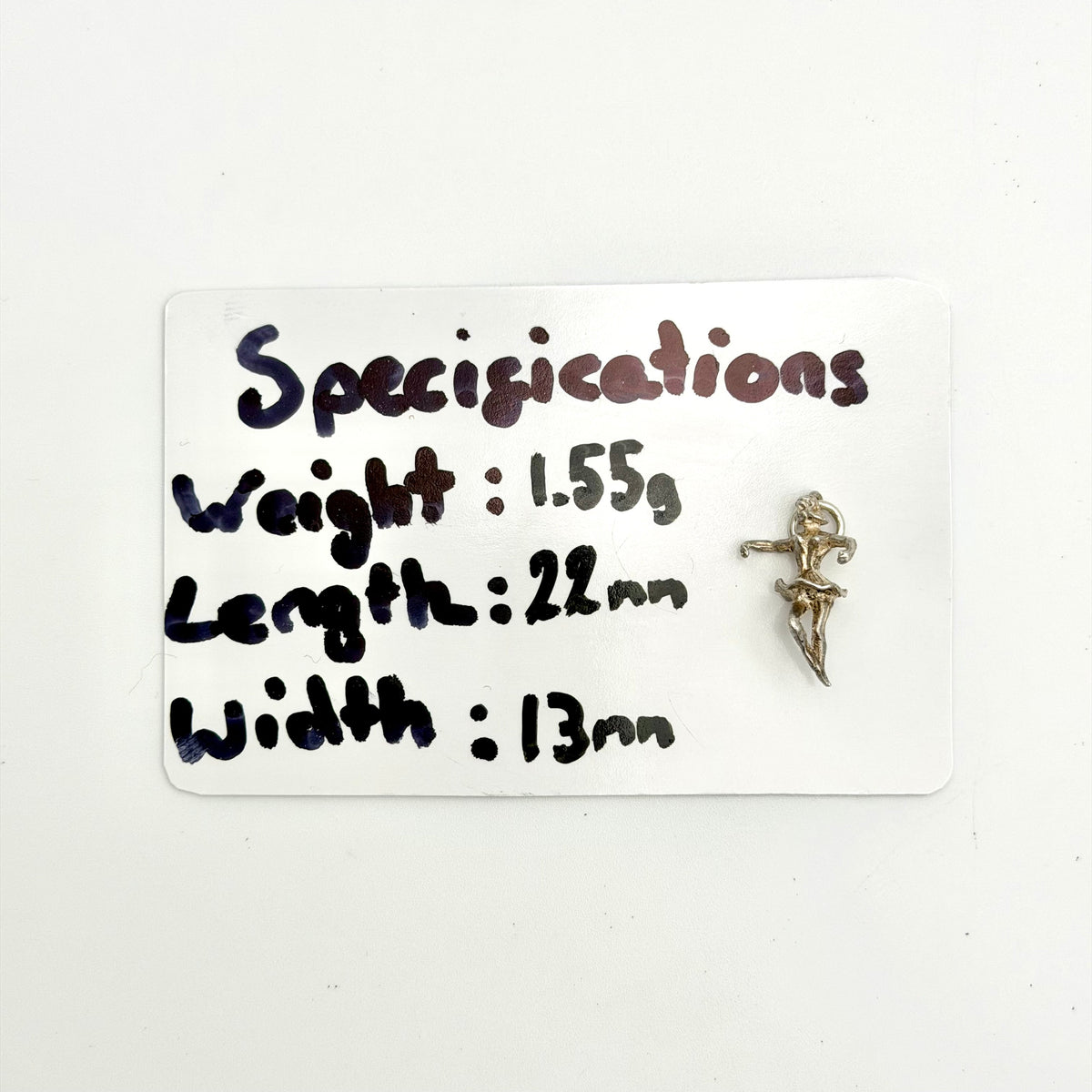 A Silver Ballerina displayed next to a white card with handwritten specifications detailing its weight, length, and width.