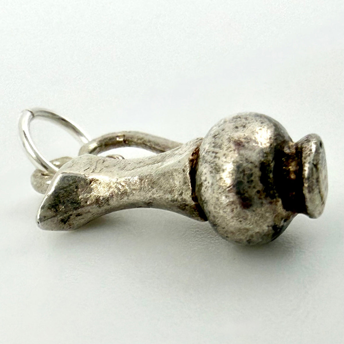 A textured sterling silver pendant shaped like a small vase or urn, featuring a rustic, speckled finish and a split bail with a jump ring, shown on a light gray background.