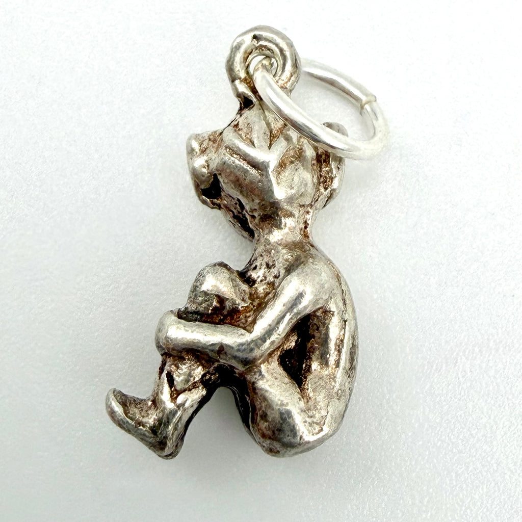Seated imp pixie charm beside a ten pence coin for scale