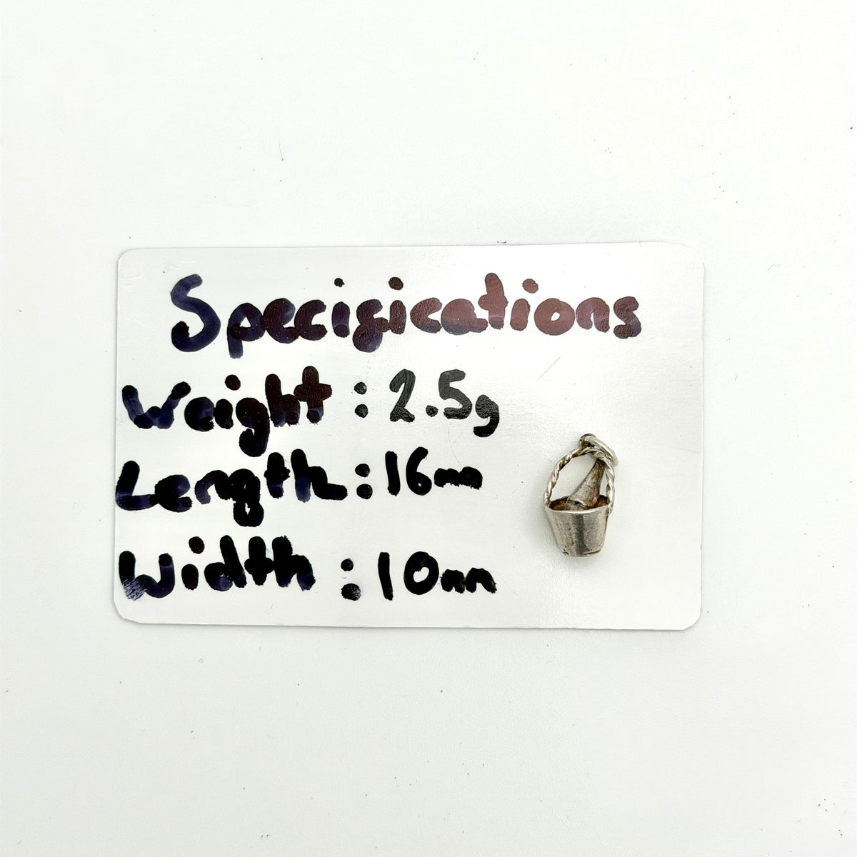 A small silver metal charm shaped like a hanging basket is shown next to a white card labeled 'Specifications' with handwritten measurements and weight.