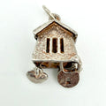A small house-shaped pendant charm in textured silver-tone metal with a lock and key motif, photographed on a plain white background.