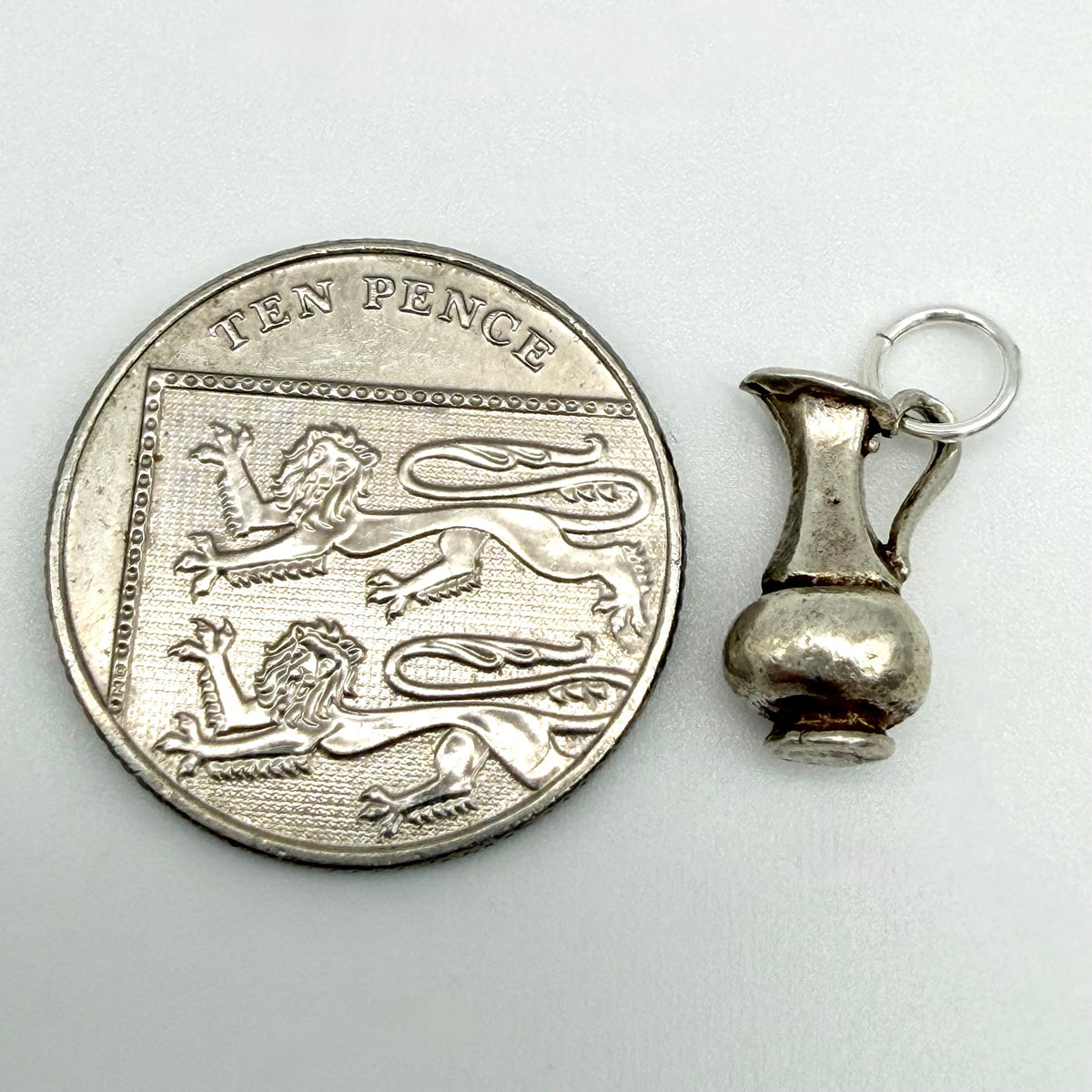 Reverse view of vintage sterling silver Aquarius water jug charm with rounded base and hanging ring