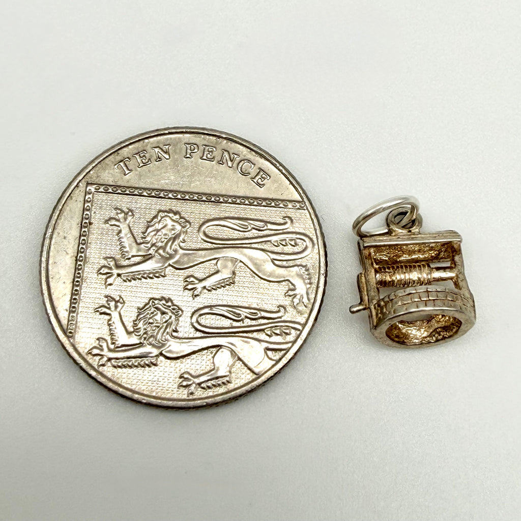 Vintage sterling silver wishing well charm beside ten pence coin for scale