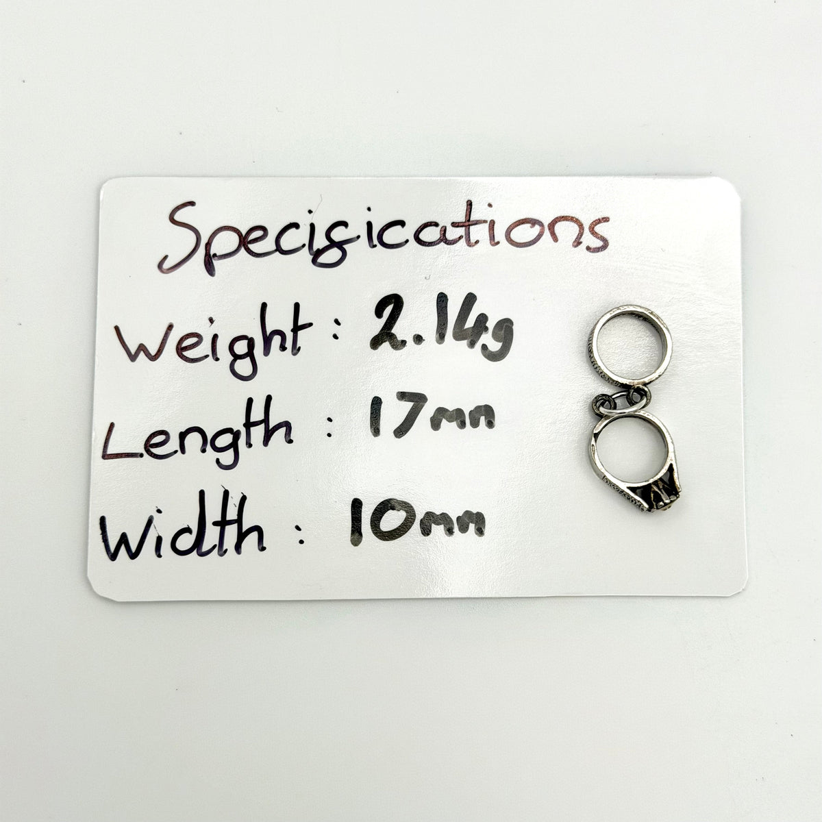 Vintage linked rings charm beside a ten pence coin for scale