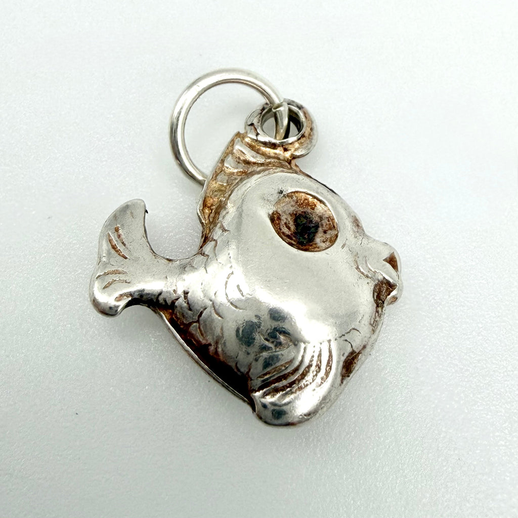 Vintage sterling silver fish charm seen from the front with chunky engraved scales, a large round eye, open mouth and a silver suspension ring