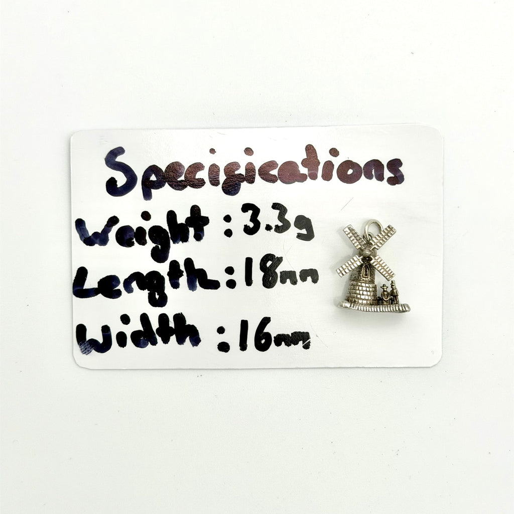 A small silver windmill charm displayed on a white card with handwritten specifications detailing its weight, length, and width.