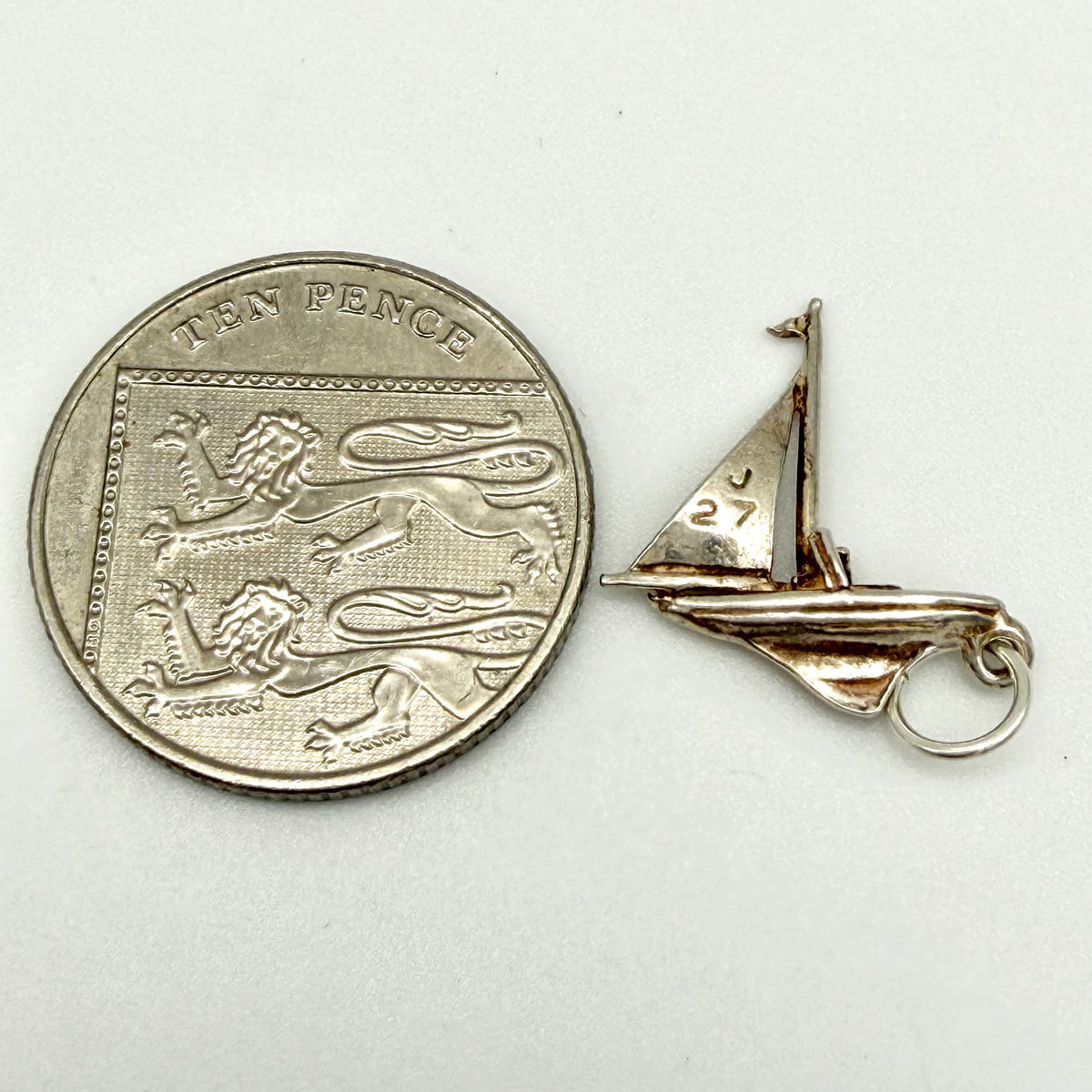 Reverse angle of the sailboat charm showing the hull and jump ring