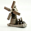 A silver-toned metal charm shaped like a windmill with two small figures and a dog beside it, photographed on a plain white background.