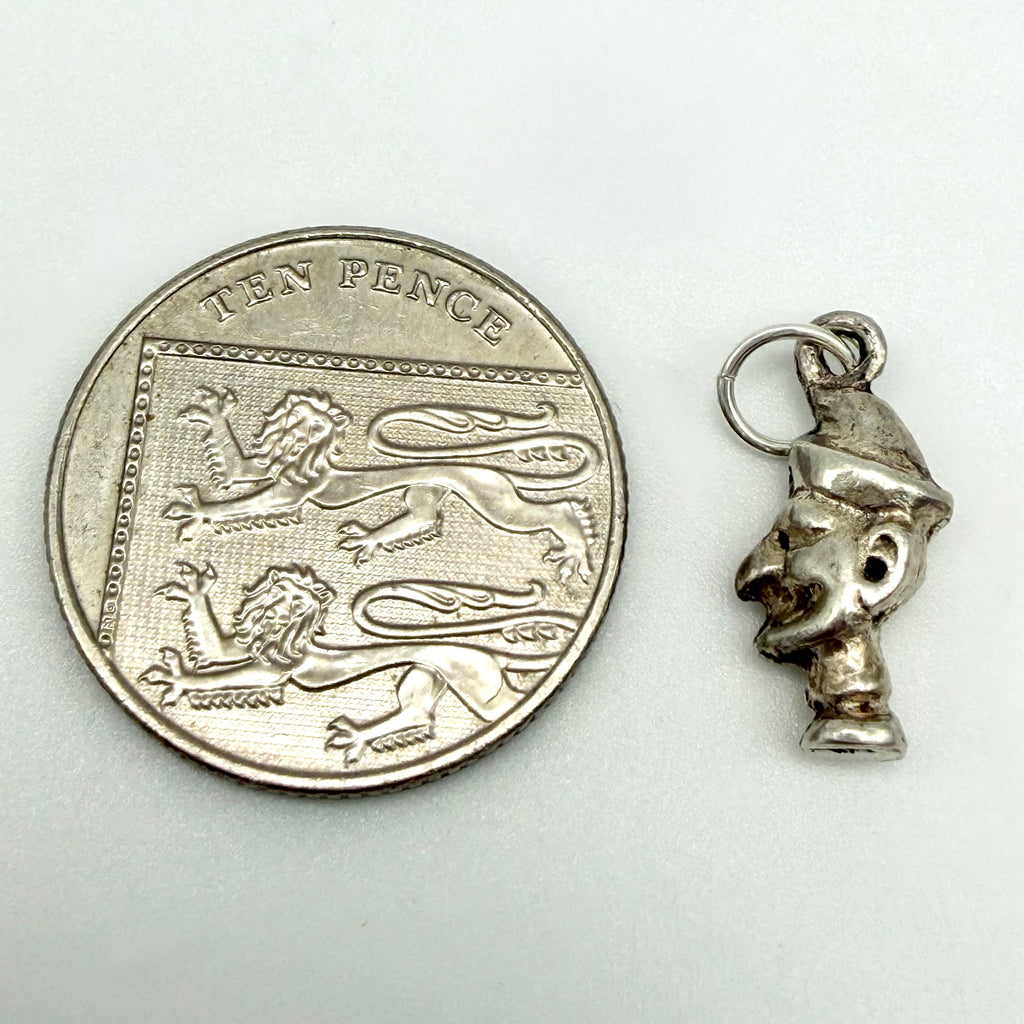Sterling silver Mr Punch charm beside a ten pence coin for scale