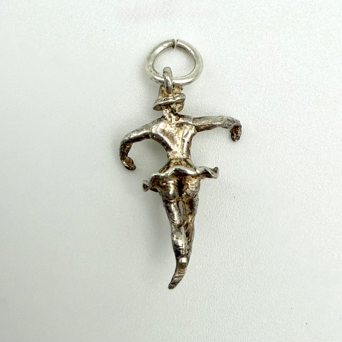 A sterling silver pendant charm shaped like a dancing figure, featuring a textured finish and a circular ring at the top, shown on a plain light background.