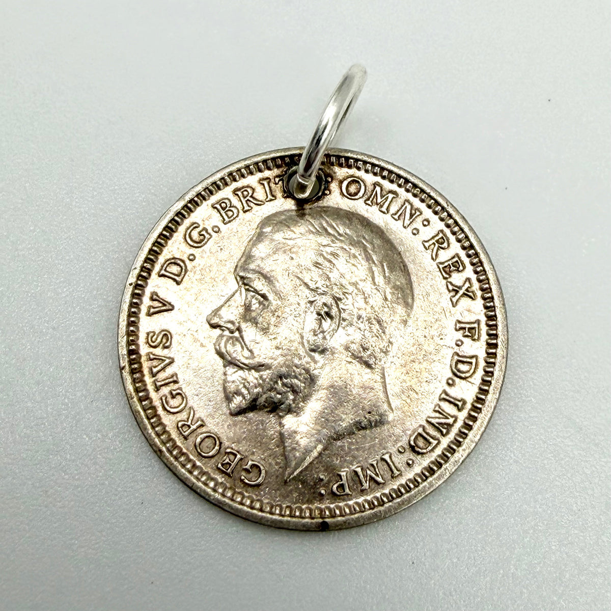 Close view of oak leaves and acorns on the 1933 threepence silver coin charm
