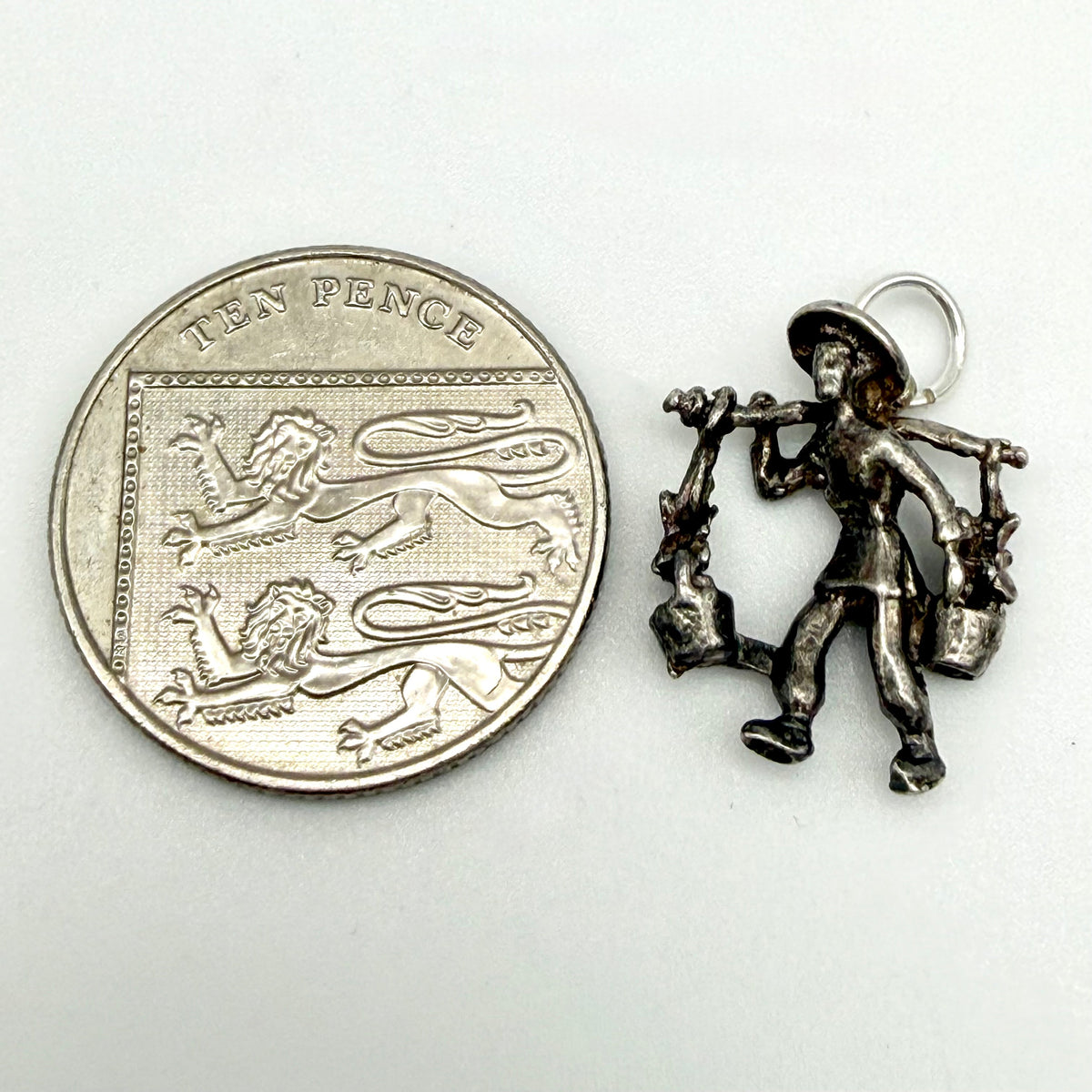 Angled view showing the back and underside of the silver water carrier charm
